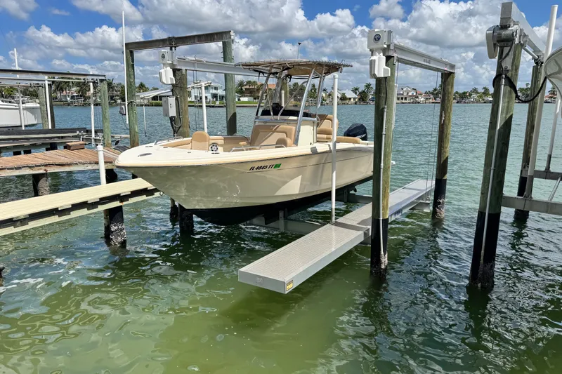 Slide: The Image of 2022 Scout 215 XSF boat on lift at marina, sunny day, calm water. - 48