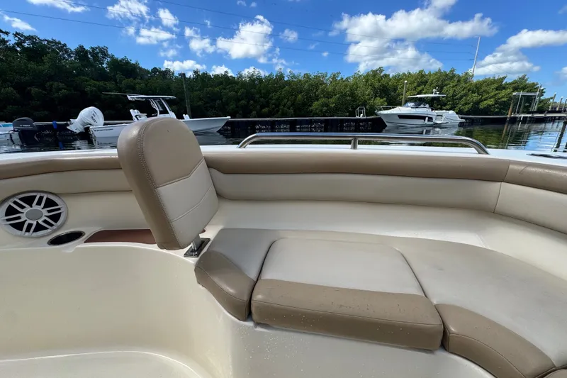 Slide: The Image of 2022 Scout 215 XSF boat interior with beige seating, docked near lush greenery. - 17