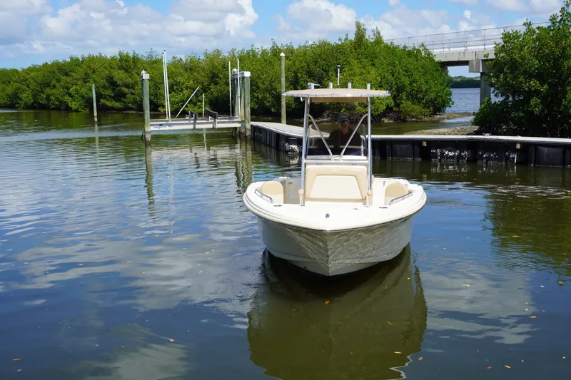 Slide: The Image of 2022 Scout 215 XSF boat on calm water near a dock and lush greenery. - 4