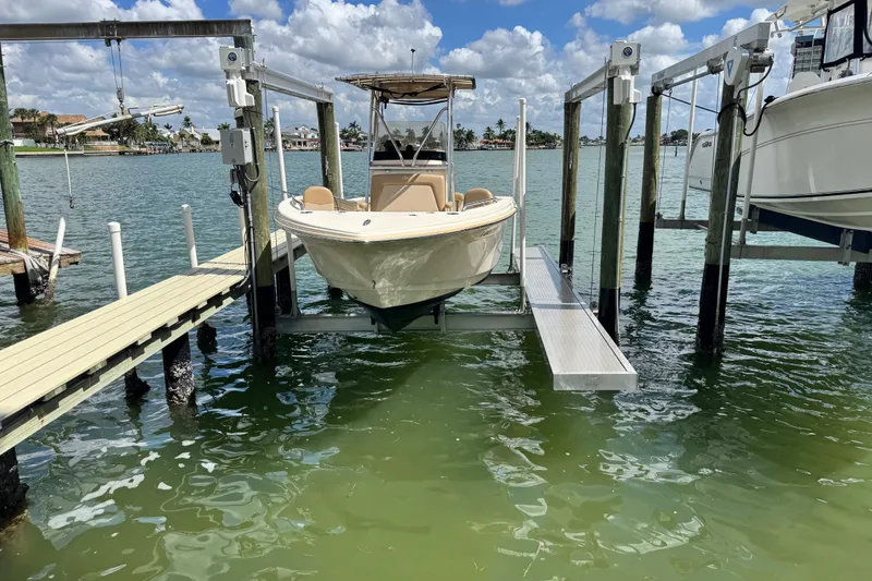 Slide: The Image of 2022 Scout 215 XSF boat on lift at marina, under blue sky. - 47
