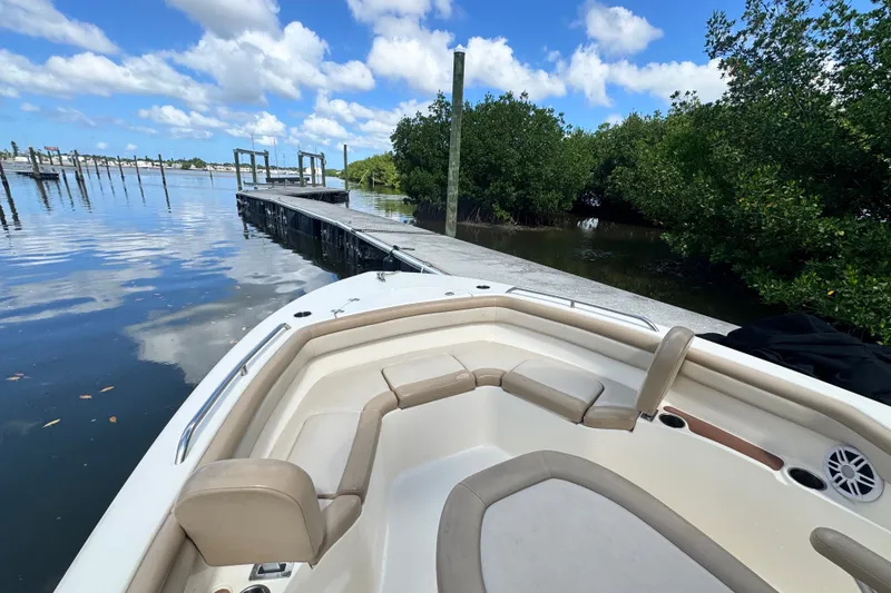 Slide: The Image of 2022 Scout 215 XSF boat docked by a serene waterfront under a blue sky. - 15