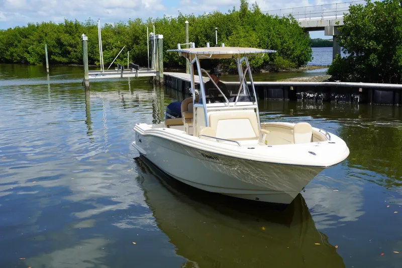Slide: The Image of 2022 Scout 215 XSF boat docked in a serene waterway with lush greenery. - 3
