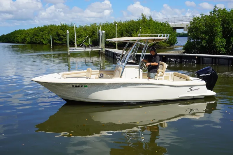 The Image of 2022 Scout 215 XSF boat on calm water near a dock, under a clear sky. - 1