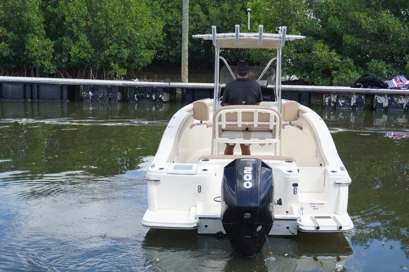 Slide: The Image of 2022 Scout 215 XSF boat with Mercury 200 engine, docked near lush greenery. - 11