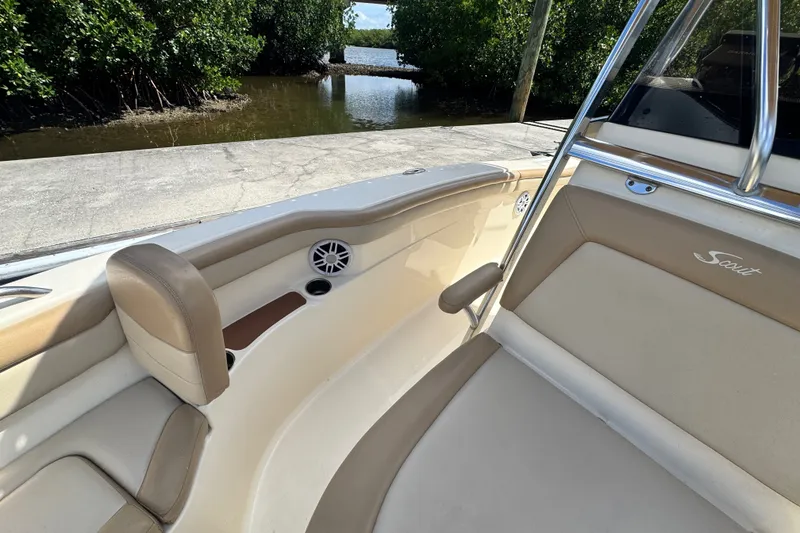 Slide: The Image of 2022 Scout 215 XSF boat interior with tan seating and speaker, near water. - 22