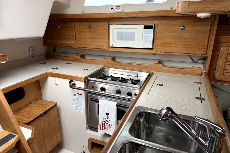 Slide: The Image of 2005 Catalina 36 MkII yacht kitchen with stove, microwave, and wooden cabinetry. - 6