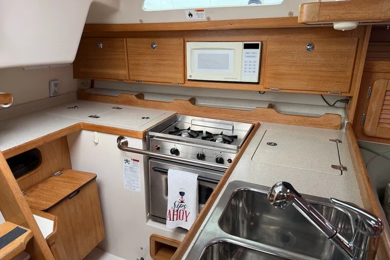 Slide: The Image of 2005 Catalina 36 MkII yacht kitchen with stove, microwave, and wooden cabinetry. - 28