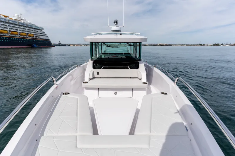 Slide: The Image of 2027 Axopar 29 XC Cross Cabin boat on calm water, with cruise ship in background. - 9