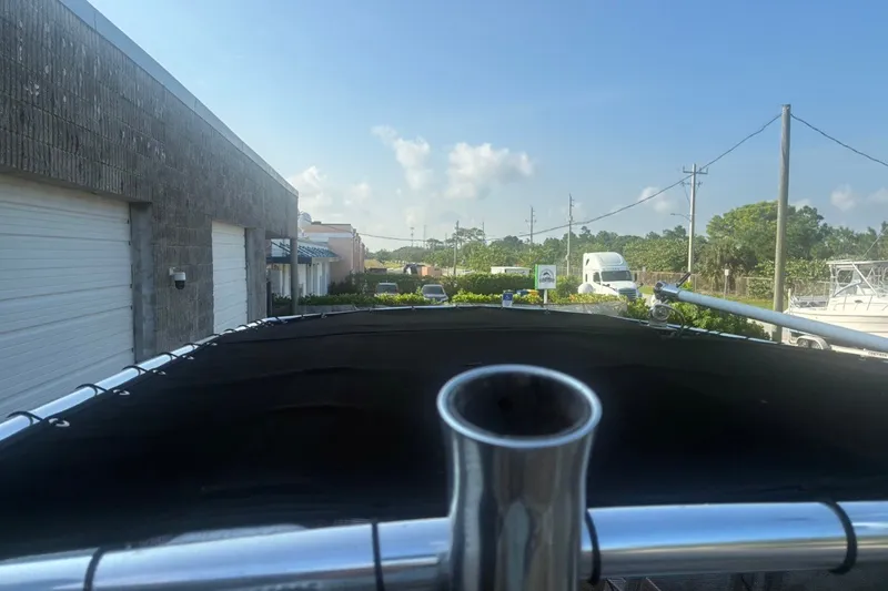 Slide: The Image of 2020 Key West 203 FS boat with black canopy, parked near industrial buildings. - 33