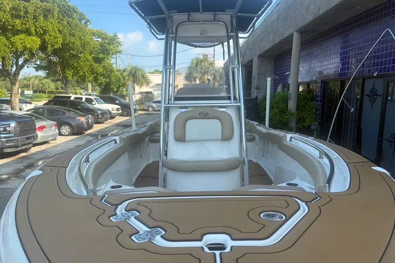Slide: The Image of 2020 Key West 203 FS boat with tan seating, parked outdoors near cars and trees. - 19