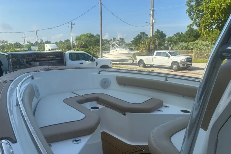 Slide: The Image of 2020 Key West 203 FS boat interior with cushioned seating, parked trucks in background. - 16