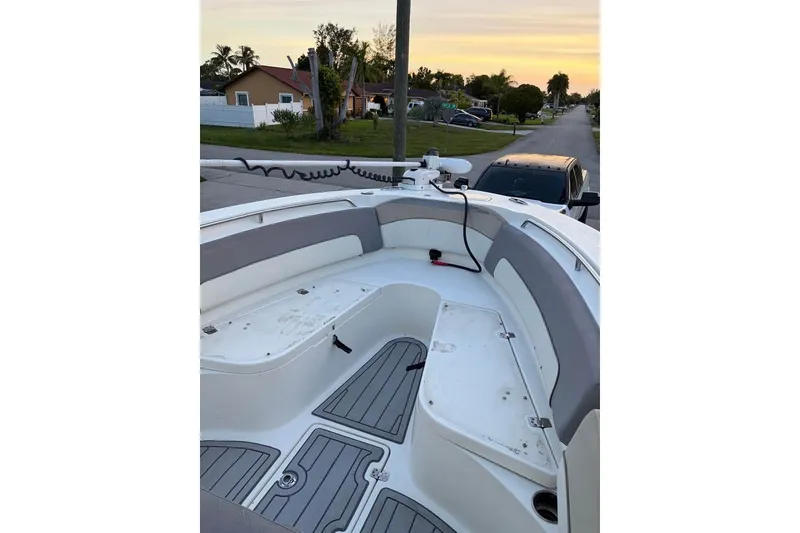 Slide: The Image of 2015 NauticStar 2500XS Offshore boat interior with seating and storage, parked in a residential area. - 7