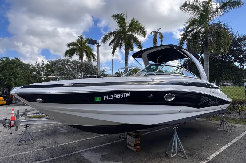Slide: The Image of 2022 Crownline Eclipse E285 XS boat on stands, surrounded by palm trees. - 2