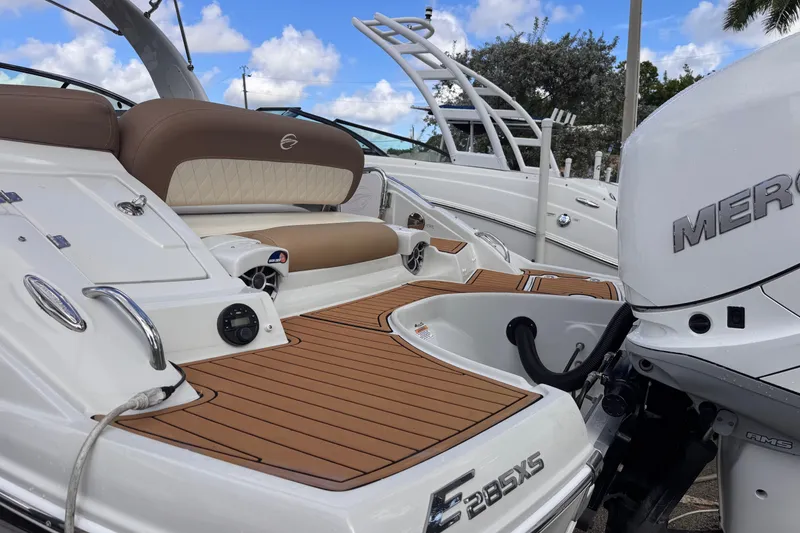 Slide: The Image of 2022 Crownline Eclipse E285 XS boat with Mercury engine, featuring teak deck and cushioned seating. - 6