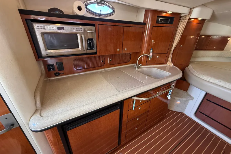 Slide: The Image of 2007 Sea Ray 340 Sundancer interior kitchen with microwave, sink, and wooden cabinetry. - 31