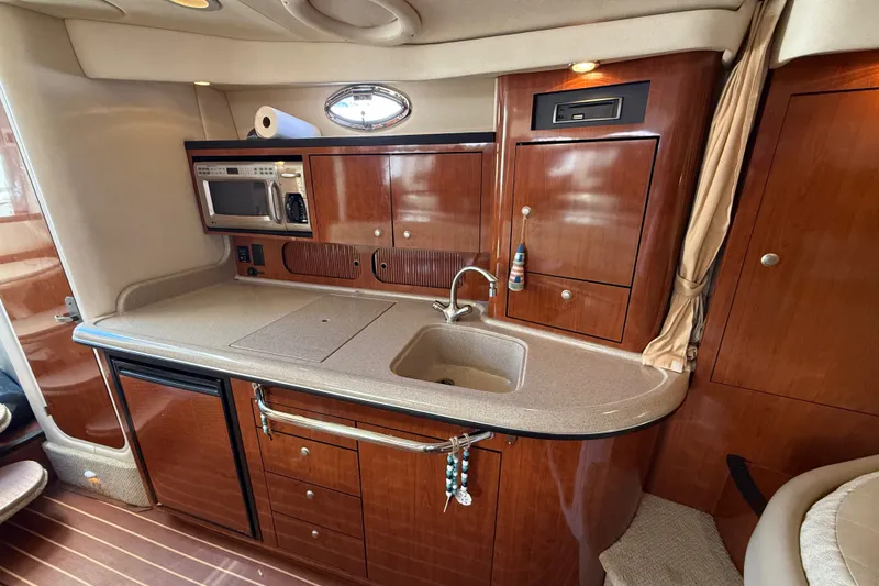 Slide: The Image of 2007 Sea Ray 340 Sundancer galley with wood cabinetry, sink, microwave, and compact fridge. - 32