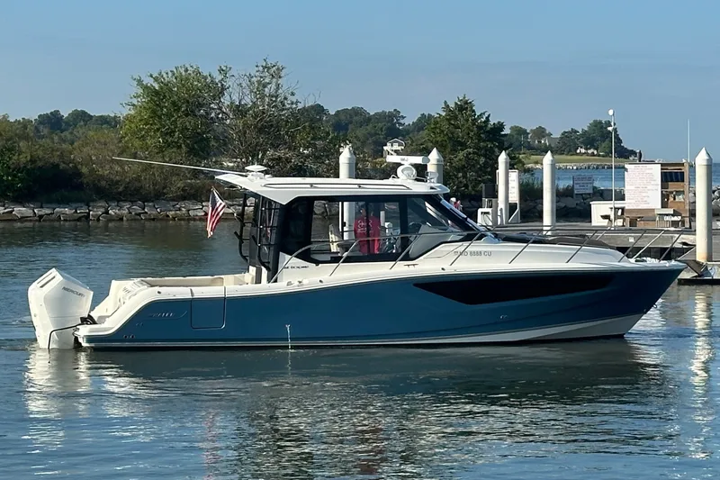 Slide: The Image of 2025 Boston Whaler 365 Conquest boat docked in a serene marina setting. - 2