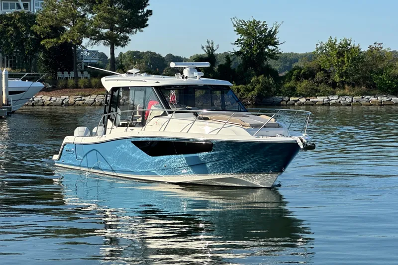 Slide: The Image of 2025 Boston Whaler 365 Conquest boat on calm water, surrounded by lush greenery. - 3