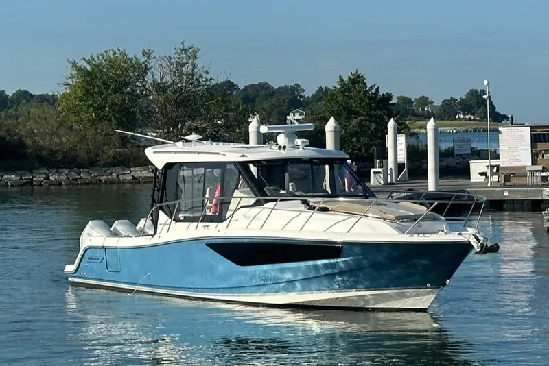Slide: The Image of 2025 Boston Whaler 365 Conquest boat docked in a serene marina setting. - 1