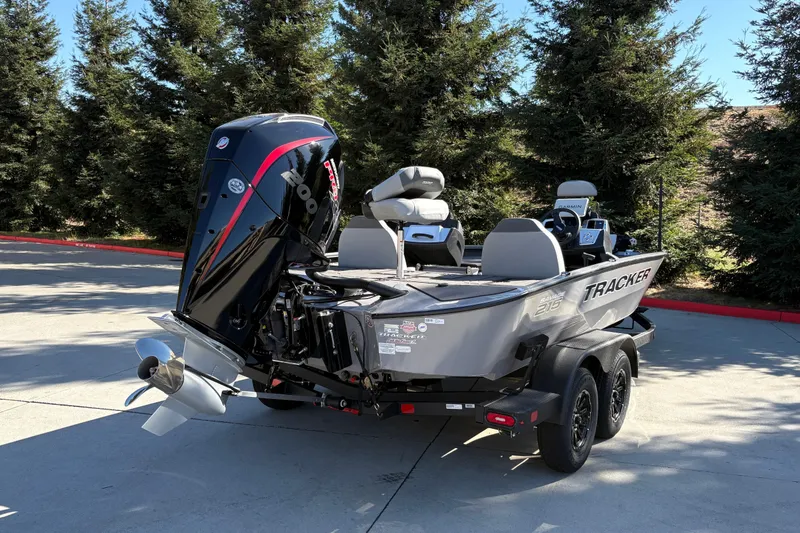 Slide: The Image of 2027 Tracker Savage 215 boat on trailer, parked outdoors with trees in background. - 15