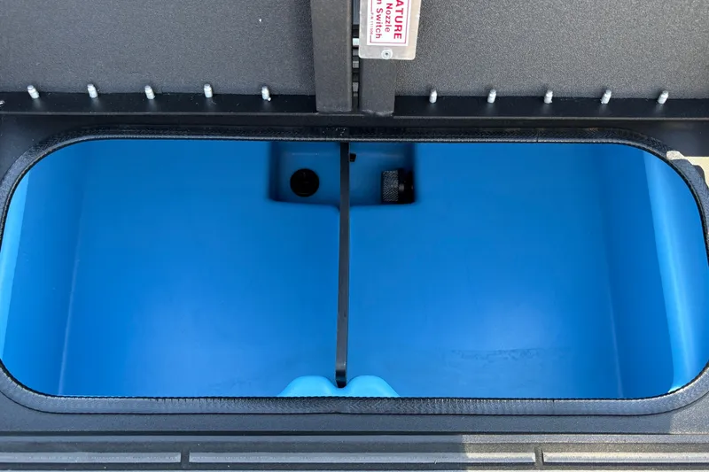 Slide: The Image of Open storage compartment of 2027 Tracker Savage 215 boat, featuring a blue interior. - 38