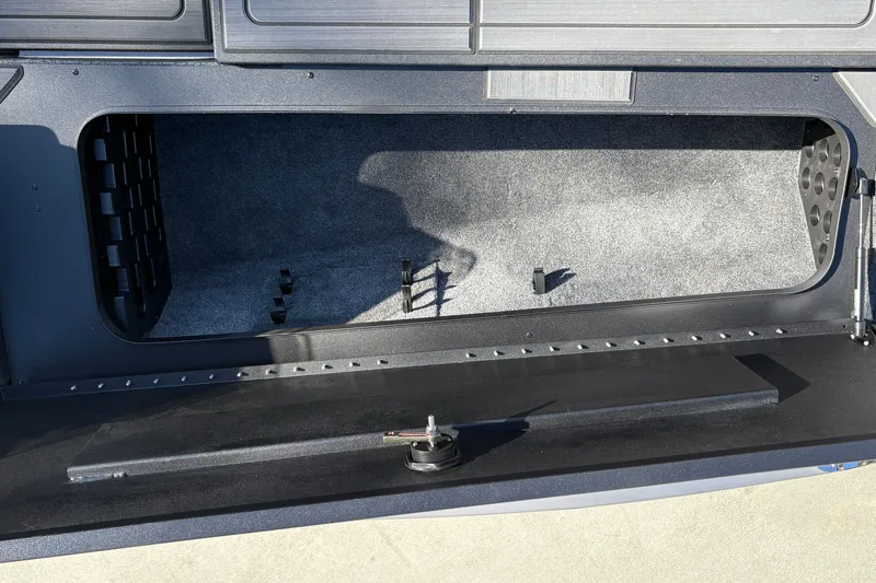Slide: The Image of Open storage compartment of 2027 Tracker Savage 215 boat, featuring carpeted interior and secure latch. - 28