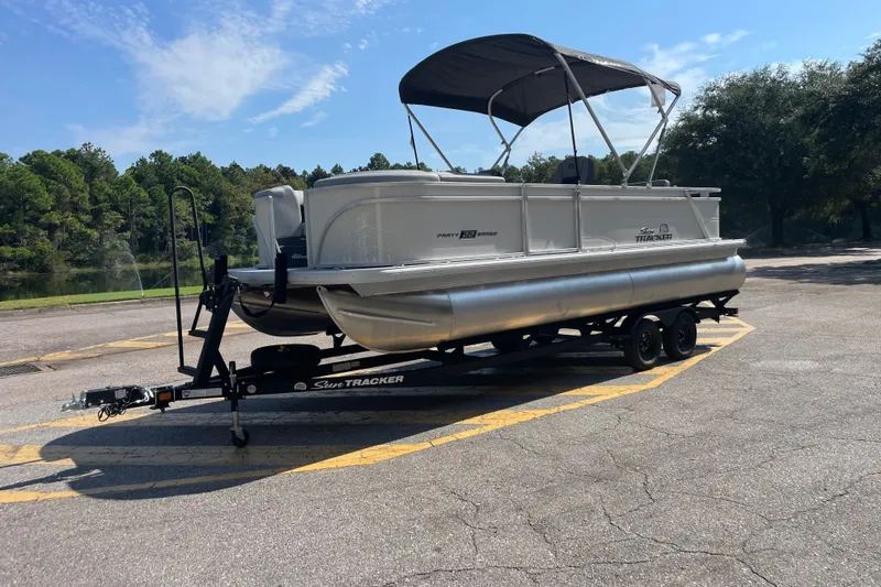 The Image of 2027 Sun Tracker Party Barge 22 RF DLX pontoon boat on trailer, parked outdoors. - 0