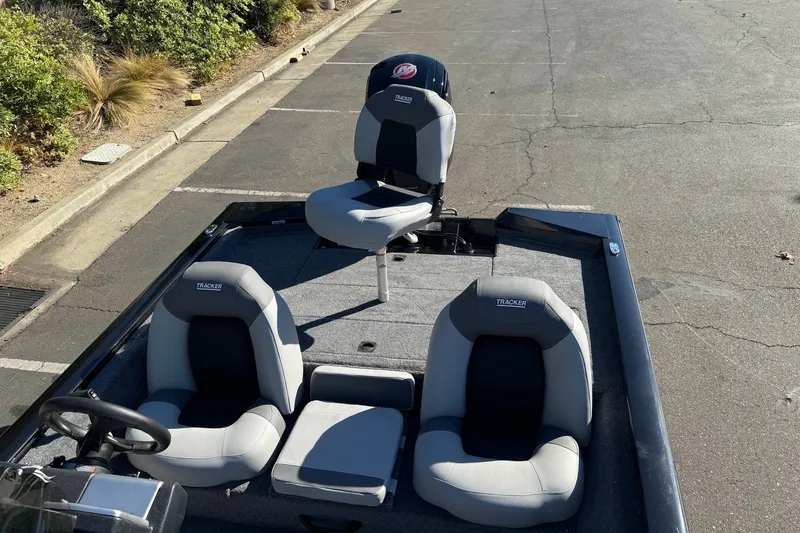 Slide: The Image of 2027 Tracker Pro Team 190 boat interior with three gray seats in a parking lot. - 13