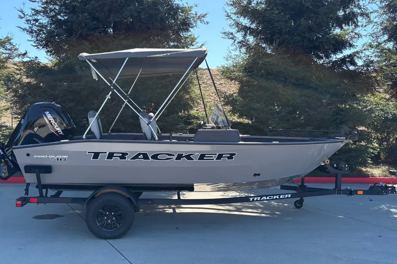 The Image of 2027 Tracker Pro Guide V-16 SC boat on trailer, parked outdoors. - 0