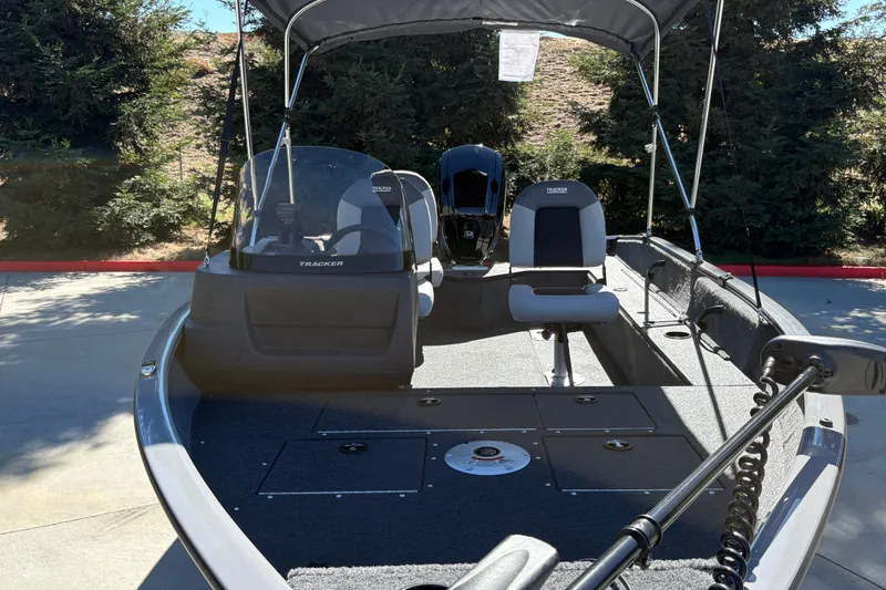 Slide: The Image of 2027 Tracker Pro Guide V-16 SC boat with seating and canopy, parked outdoors. - 18