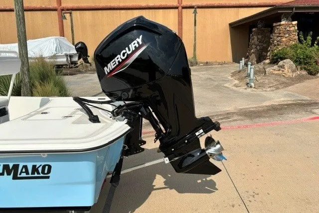 Slide: The Image of 2027 Mako Pro Skiff 17 CC with Mercury outboard motor in a driveway setting. - 17