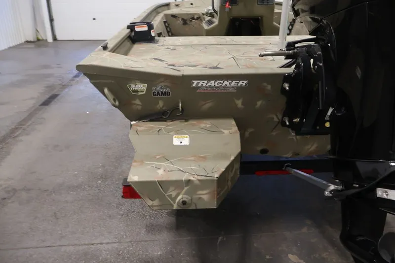 Slide: The Image of 2024 Tracker Grizzly 1860 MVX CC boat with camo design in a garage setting. - 32