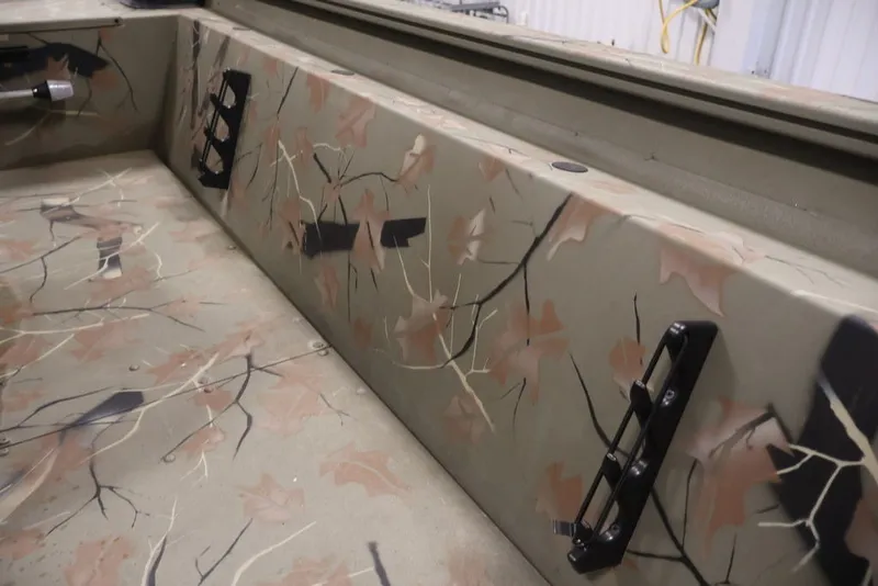 Slide: The Image of 2024 Tracker Grizzly 1860 MVX CC interior with camouflage design and rod holders. - 19