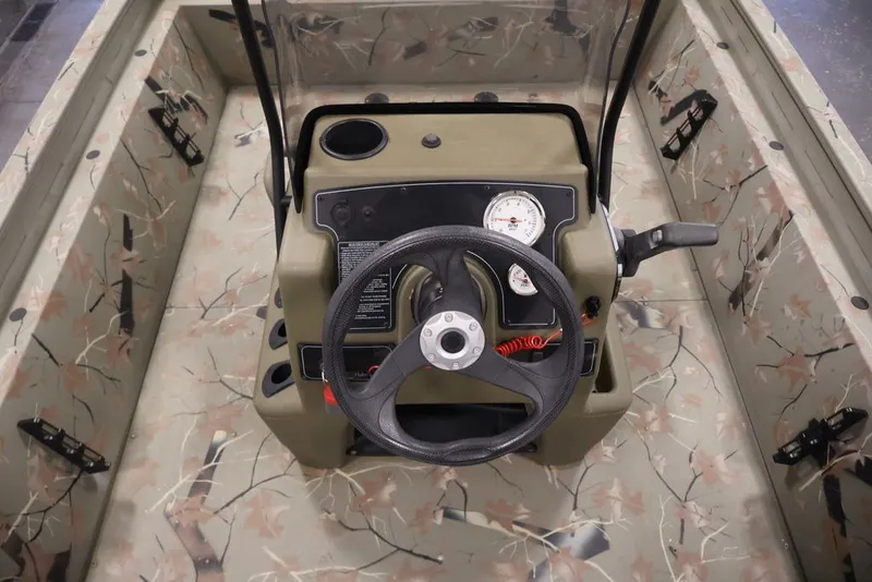 Slide: The Image of 2024 Tracker Grizzly 1860 MVX CC boat interior with camouflage design and steering console. - 26