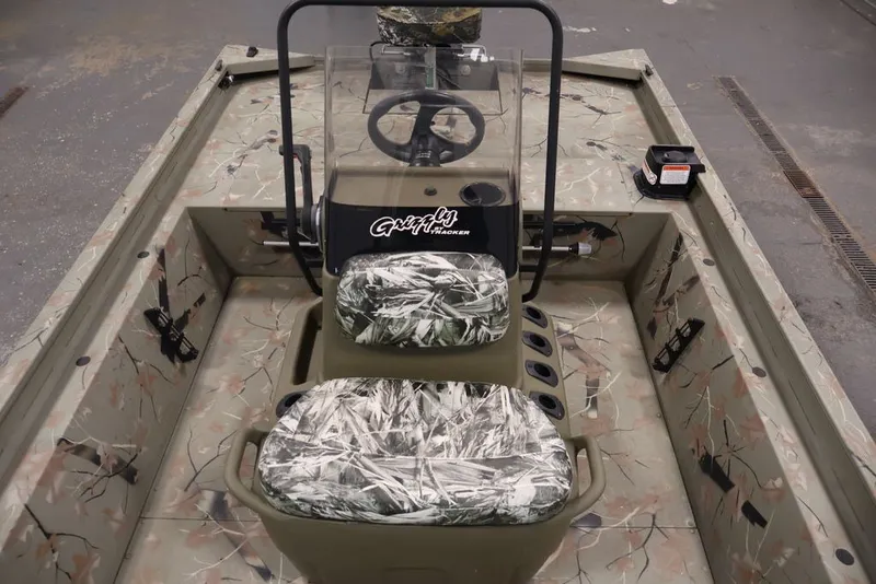 Slide: The Image of 2024 Tracker Grizzly 1860 MVX CC boat interior with camouflage seating and steering console. - 15