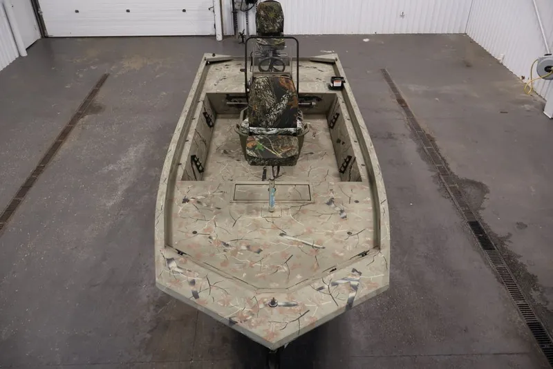 Slide: The Image of 2024 Tracker Grizzly 1860 MVX CC boat with camouflage design in a garage setting. - 16