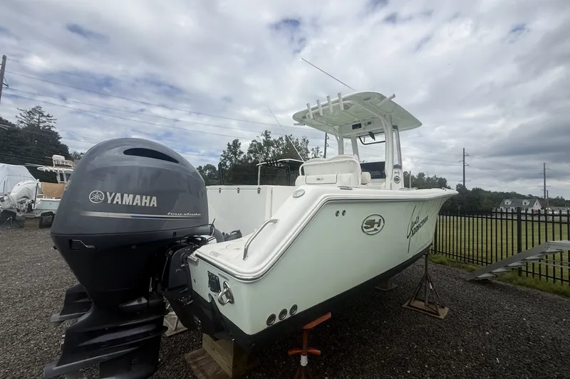 Slide: The Image of 2017 Sea Hunt Gamefish 27 boat with Yamaha engine, parked outdoors under cloudy sky. - 5