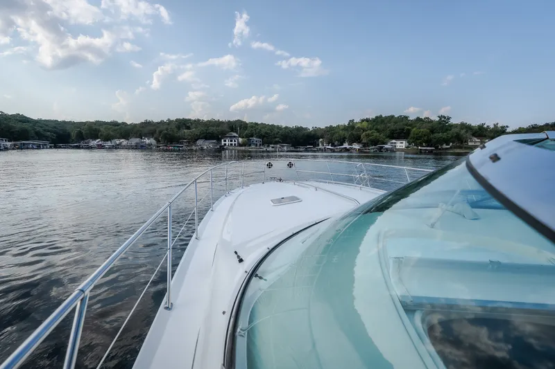 Slide: The Image of 1997 Sea Ray Sundancer 400 cruising on a serene lake with scenic shoreline views. - 63