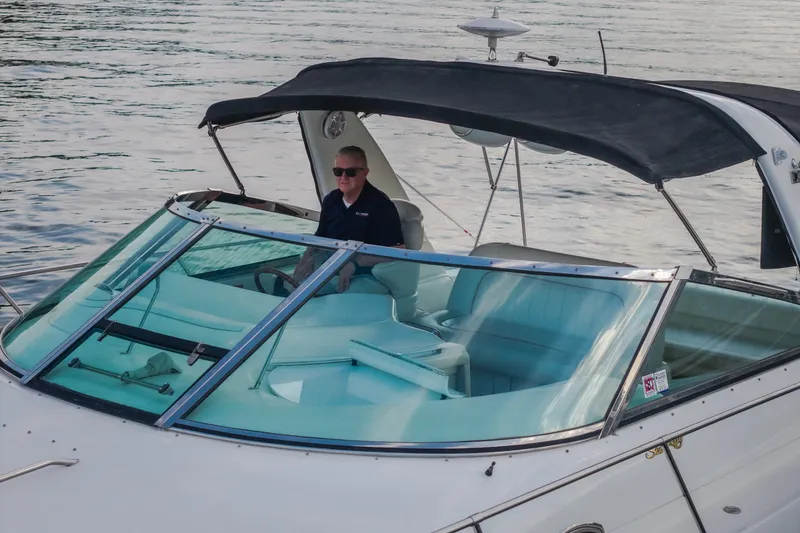 Slide: The Image of 1997 Sea Ray Sundancer 400 with a person at the helm, cruising on calm waters. - 68