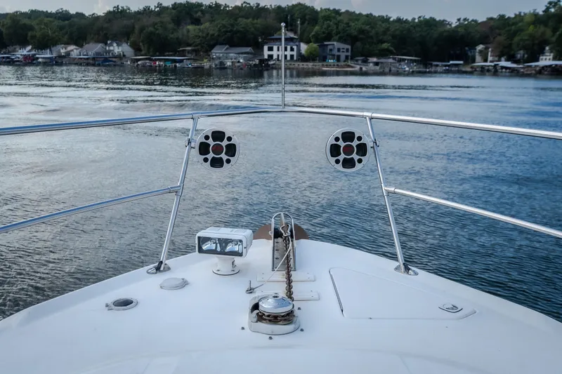 Slide: The Image of Bow view of 1997 Sea Ray Sundancer 400 on a serene lake with shoreline houses. - 29
