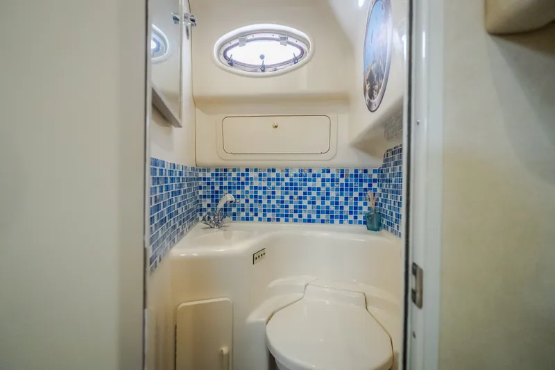Slide: The Image of Bathroom interior of 1997 Sea Ray Sundancer 400 with blue mosaic tiles and porthole window. - 49