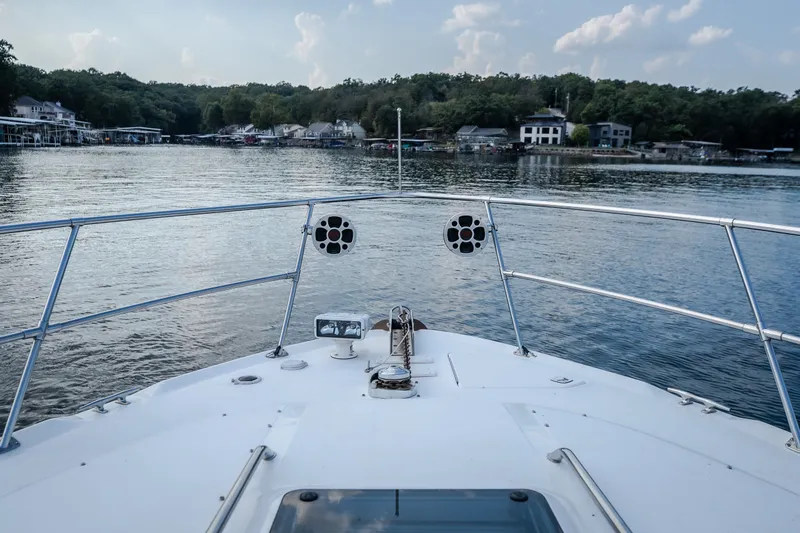 Slide: The Image of Bow view of 1997 Sea Ray Sundancer 400 on a serene lake with shoreline houses. - 44