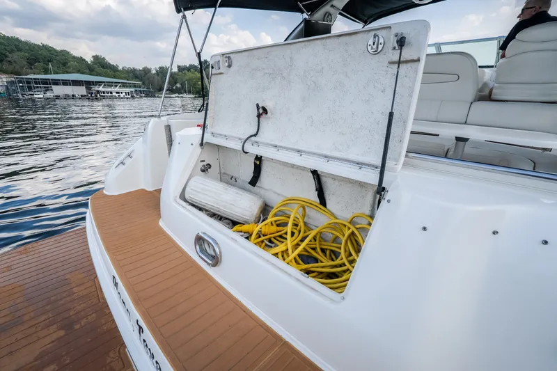 Slide: The Image of 1997 Sea Ray Sundancer 400 boat with open storage compartment, yellow cables, and scenic marina view. - 7