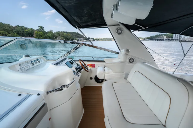 Slide: The Image of 1997 Sea Ray Sundancer 400 yacht cockpit with white seating and steering, overlooking serene waters. - 34