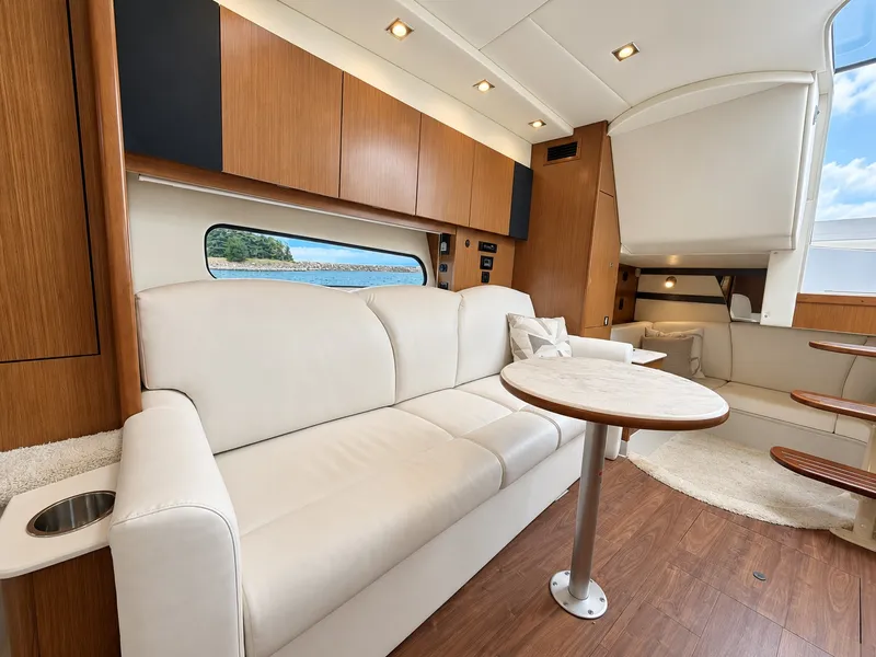 Slide: The Image of Interior of a 2020 Cruisers Yachts 35 Express with elegant white couch and wooden table. - 44