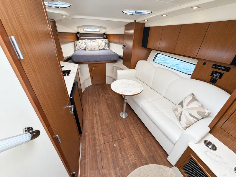 Slide: The Image of Interior of a 2020 Cruisers Yachts 35 Express with wood flooring, white sofa, and sleeping area. - 37