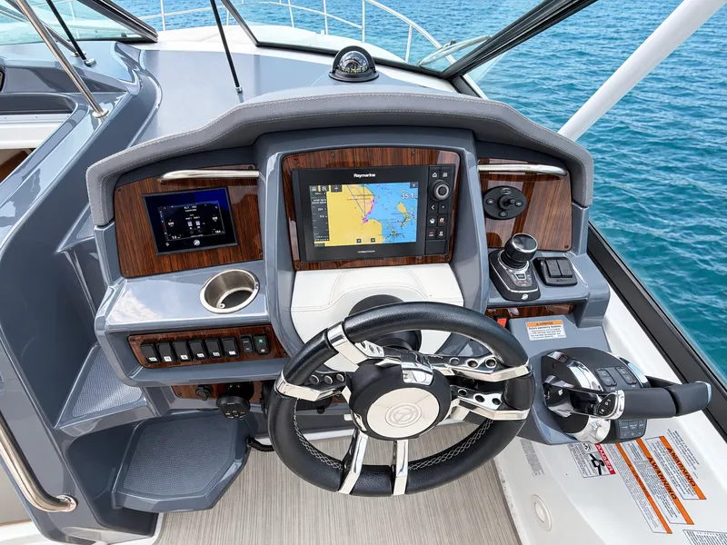 Slide: The Image of The image shows the helm of a 2020 Cruisers Yachts 35 Express. It features a modern navigation system, stylish steering wheel, and wood accents. - 29
