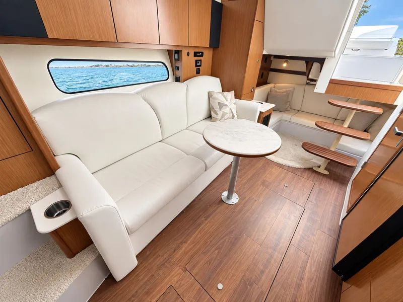 Slide: The Image of Interior of a 2020 Cruisers Yachts 35 Express with elegant leather couch and wooden flooring. - 42