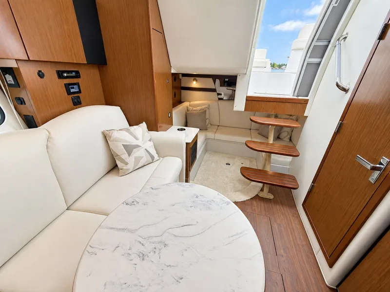 Slide: The Image of The interior cabin of the 2020 Cruisers Yachts 35 Express features an elegant seating area with a round marble table and comfortable upholstery. - 45