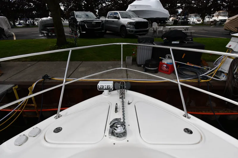 Slide: The Image of Bow view of 2004 Sea Ray 420 Sundancer docked, with parked vehicles in background. - 4